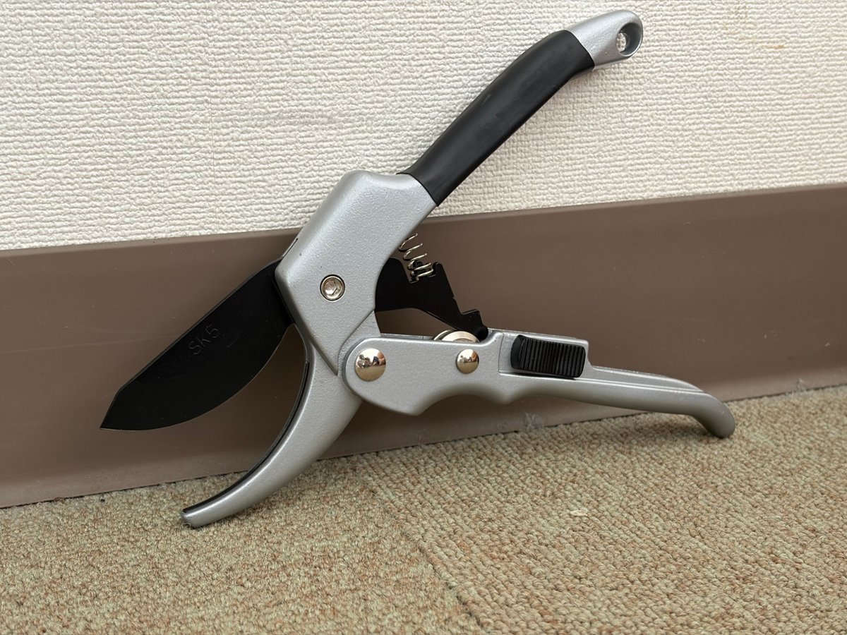 壁に立てかけた、刃を開いた状態の剪定ばさみ