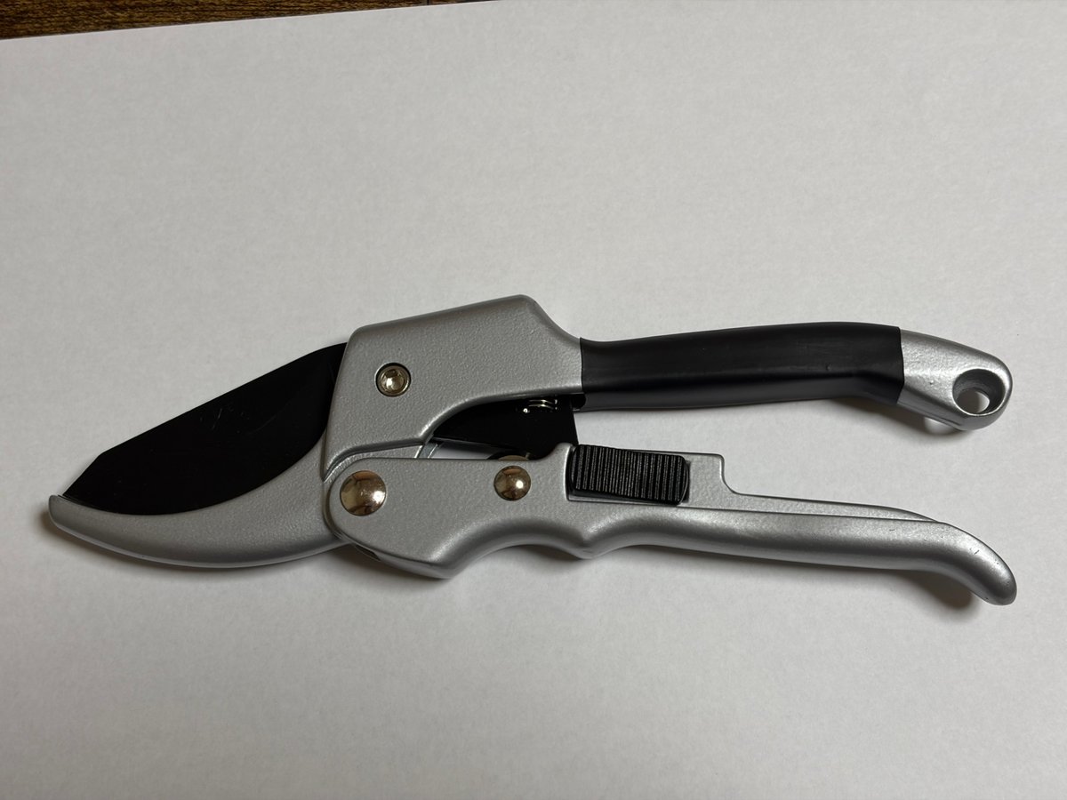 刃を閉じた状態の片手用剪定ばさみ全体(白い紙の上)
